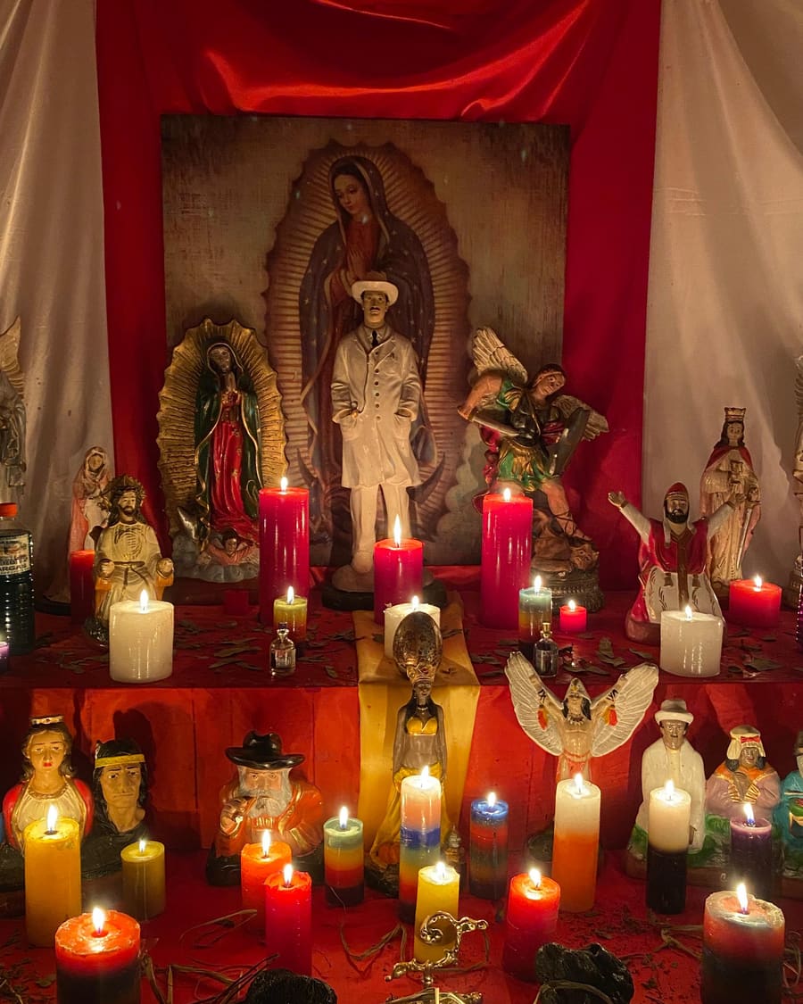 Mi altar: la Virgen de Guadalupe al centro, ángeles, santos y veladoras de colores encendidas.